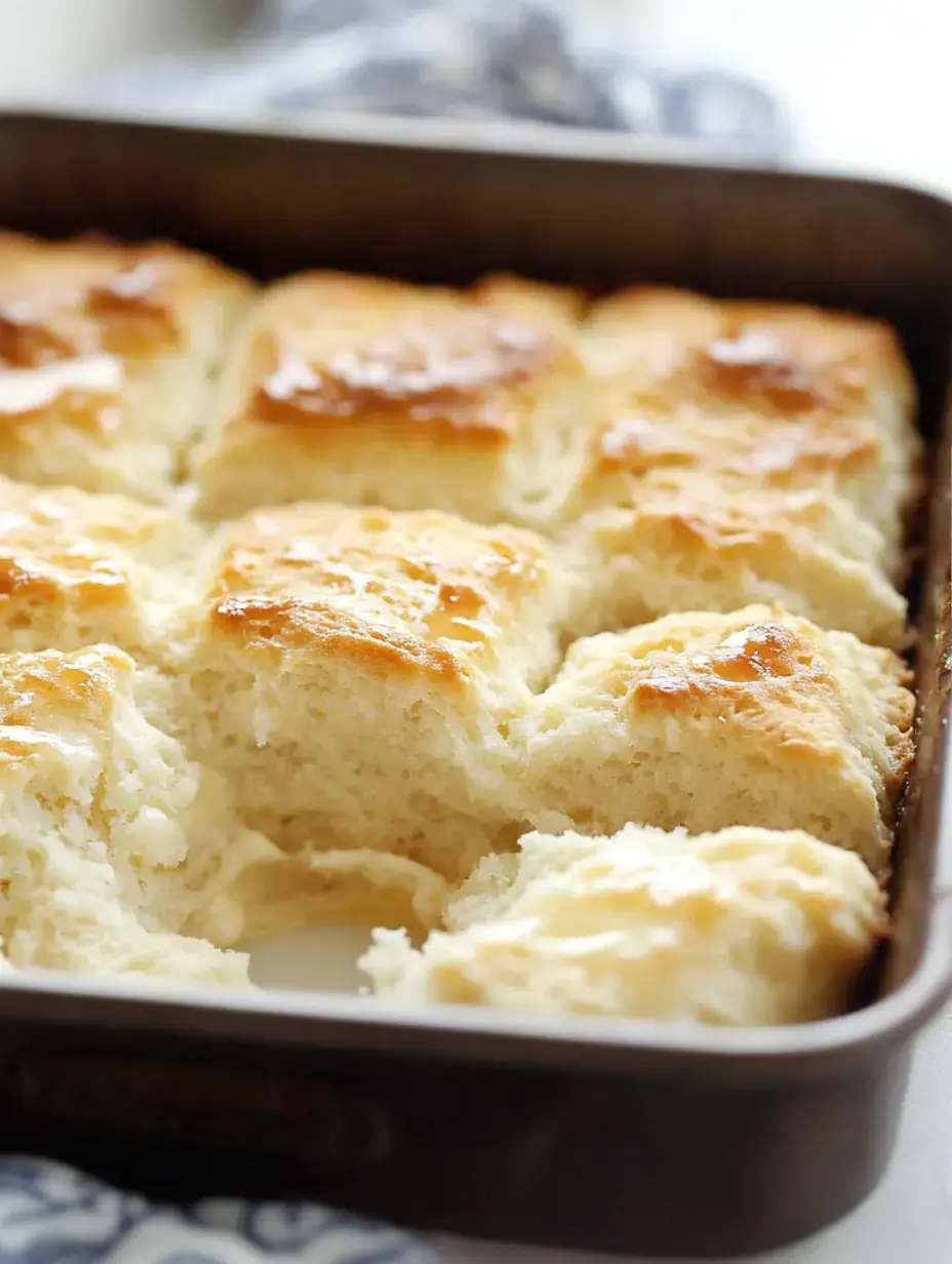 Ein frisch gebackenes Blech goldbrauner Kekse, wobei einige Stücke auseinandergezogen sind und ihr fluffiges Inneres zeigen.