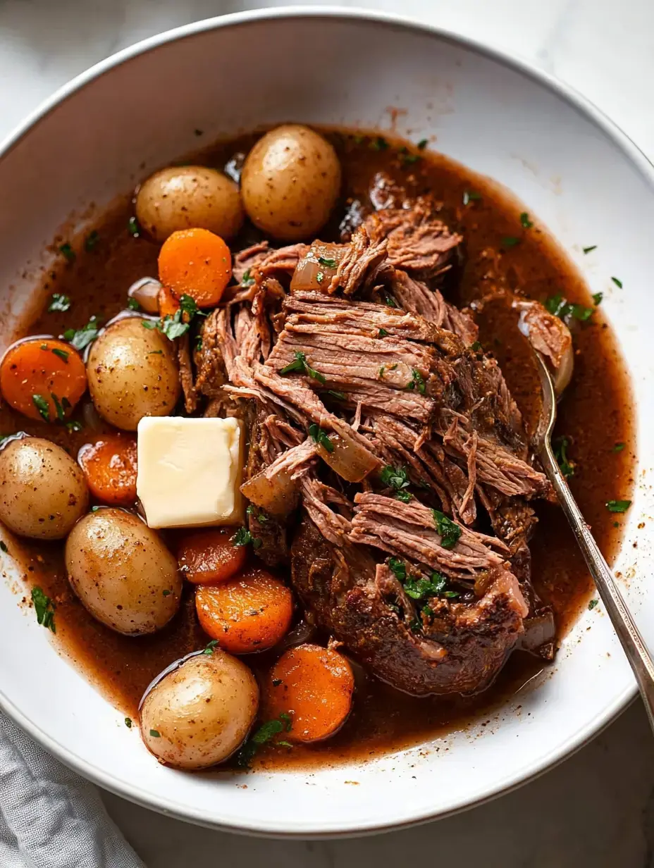 Eine Portion zartes, zerfasertes Rindfleisch mit kleinen Kartoffeln und Karotten, gekrönt mit einem Stück Butter und mit Petersilie garniert in einer weißen Schüssel.