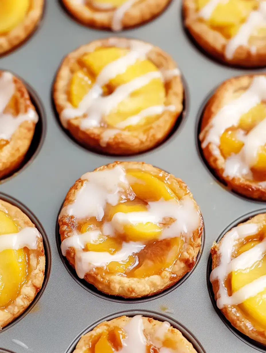 Eine Nahaufnahme von Mini-Obsttörtchen mit Pfirsichscheiben und einem Hauch Zuckerguss, angeordnet in einer Muffinform.