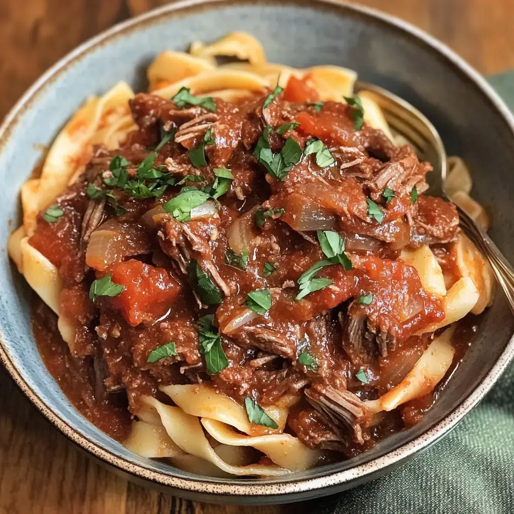 Eine Schüssel Pasta mit einer üppigen Rindfleisch-Tomatensoße und frischer Petersilie obendrauf.